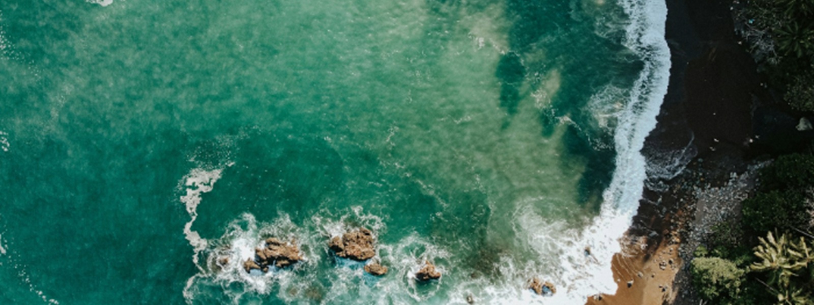 Vue aérienne d'une plage sauvage bordée de forêt tropicale, eaux turquoise et rochers, Costa Rica