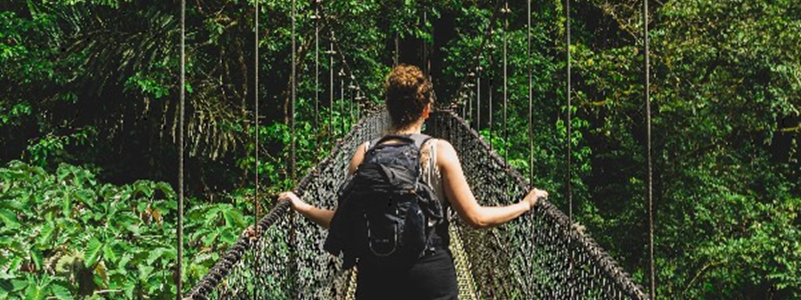 Voyageuse traversant un pont suspendu au cœur de la forêt tropicale, Costa Rica