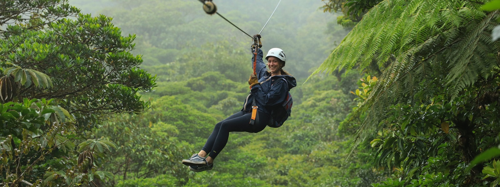 Voyageuse souriante en tyrolienne au-dessus de la forêt de nuages, Costa Rica